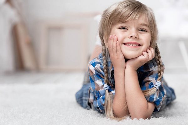 Image of a small girl laying on carpet with no chemicals due to green carpet cleaning Alpine